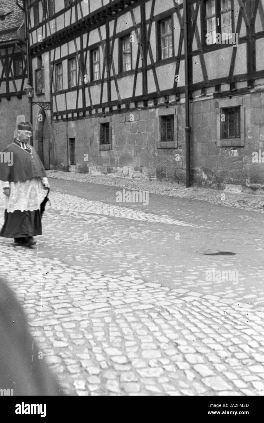Pfarrer unterwegs in einer Stadt in Bayern, Deutschland 1930er Jahre. Sacerdote il suo modo attraverso una città della Baviera, Germania 1930s. Foto Stock