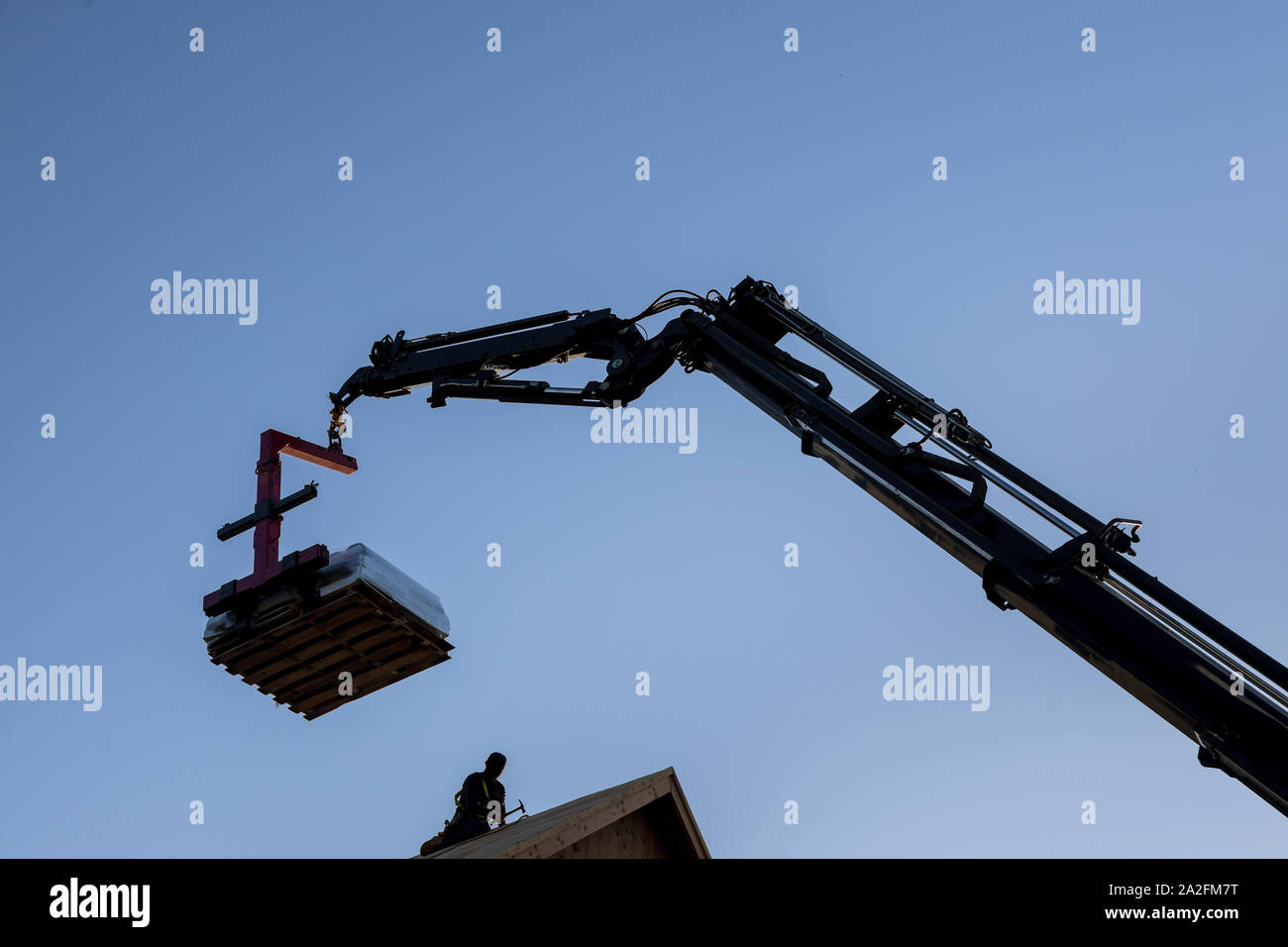 Il braccio mobile di carrello elevatore a forche offrendo materiali di preparazione sul tetto per sollevare parti di costruzione Foto Stock