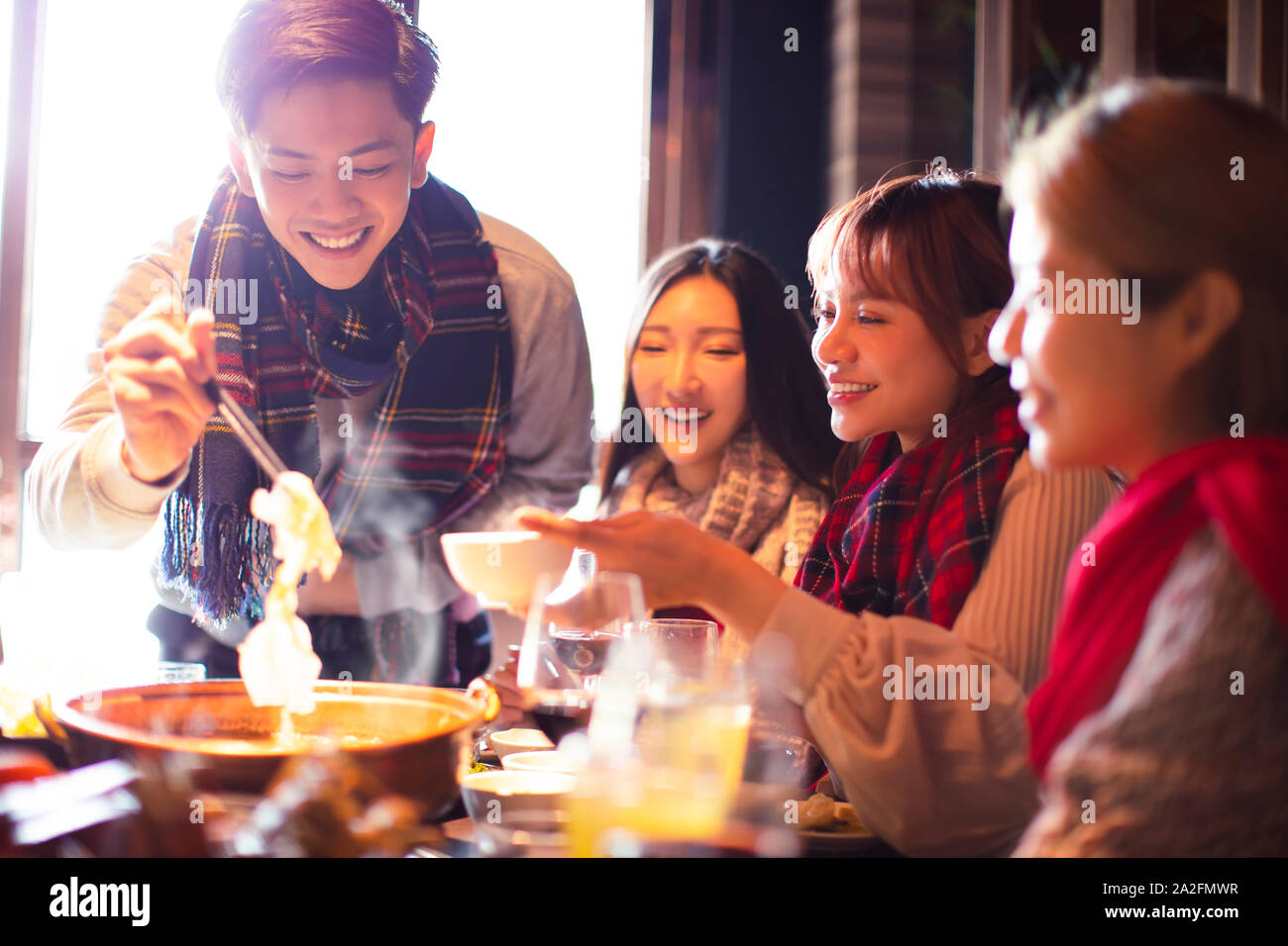 Felice giovani amici di mangiare hot pot in ristorante in inverno Foto Stock