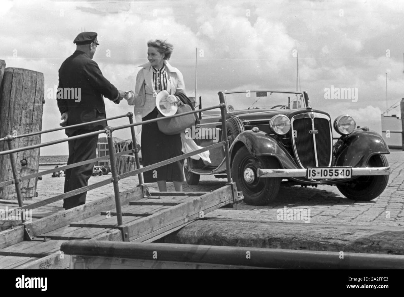 Eine Frau begrüßt einen Seemann an der passerella in Norddeich Mole vor ihrem Audi Cabrio, Deutschland 1930er Jahre. Una donna e un marinaio stringono le mani da una passerella di fronte un Audi cabrio, Germania 1930s. Foto Stock