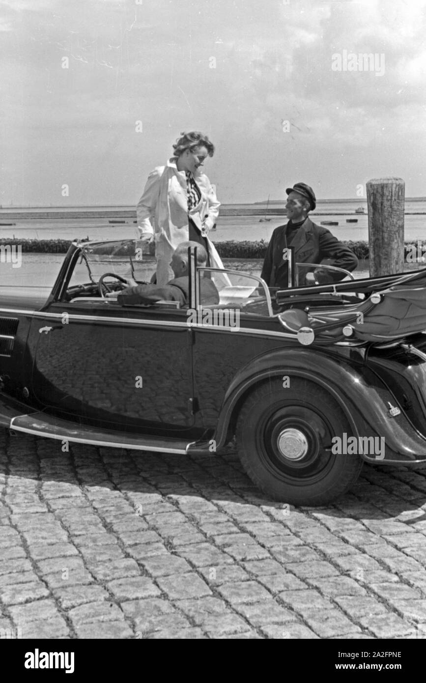 Eine Frau unterhält sich mit einem Parkwächter einer Garage in Norddeich, Deutschland 1930er Jahre. Una donna a parlare con un operatore di parcheggio di un garage di Norddeich, Germania 1930s. Foto Stock