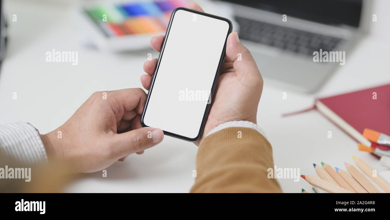 Vista ravvicinata di imprenditore tenendo premuto lo schermo è vuoto lo smartphone nel luogo di lavoro minima piena di fermo Foto Stock