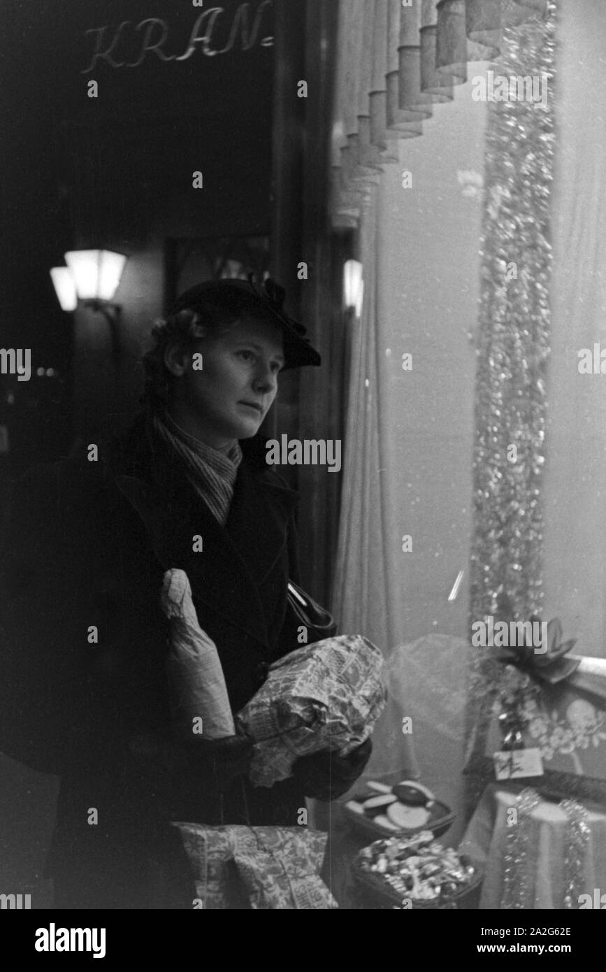Eine Frau schaut in ein Schaufenster bei ihren Weihnachtseinkäufen in der  Nähe vom Cafe Kranzler a Berlino, Deutschland 1930er Jahre. Una donna  guarda la vetrina di un negozio mentre facendo il suo