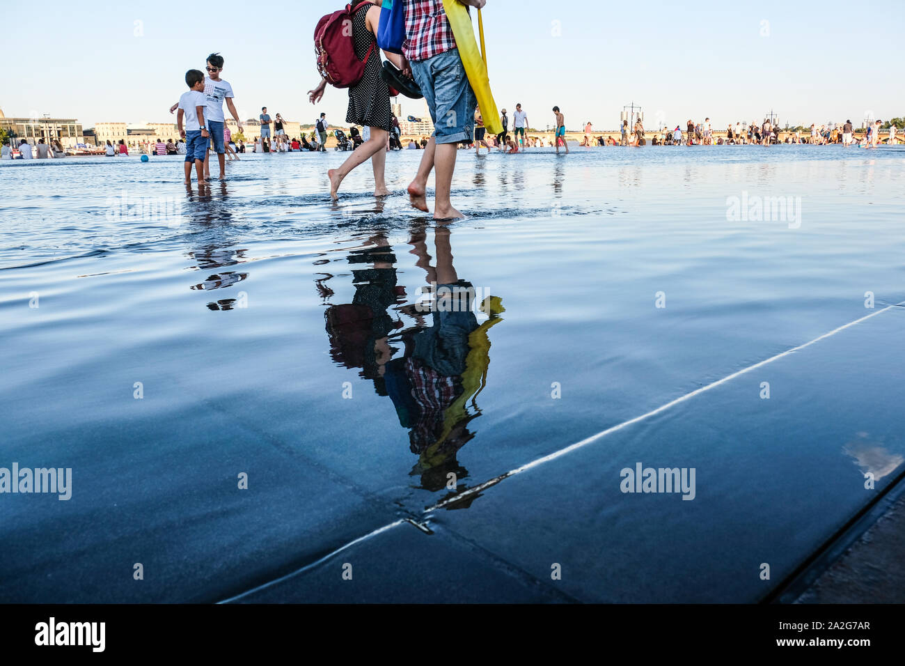 A piedi nudi persone che giocano a specchio di acqua nel centro di Bordeaux, Francia Foto Stock