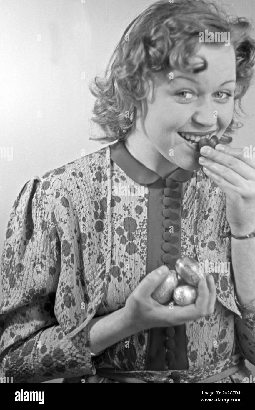 Porträt eines jungen Mädchens, essend Schokoladenostereier, Deutschland 1930er Jahre. Ritratto di una giovane ragazza di mangiare alcune uova di pasqua di cioccolato, Germania 1930s. Foto Stock