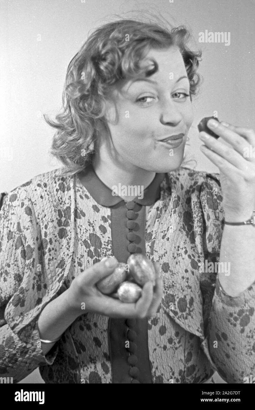 Porträt eines jungen Mädchens, essend Schokoladenostereier, Deutschland 1930er Jahre. Ritratto di una giovane ragazza di mangiare alcune uova di pasqua di cioccolato, Germania 1930s. Foto Stock