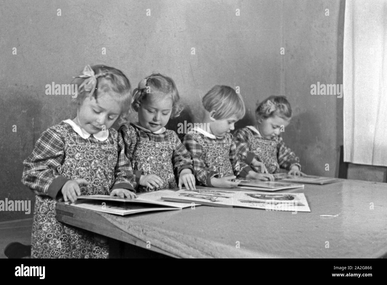 Die Vierlinge Knipser betrachten ein Bilderbuch, Deutschland 1930er Jahre. Il Knipser's quadrupletto ragazze con un storybook, Germania 1930s. Foto Stock