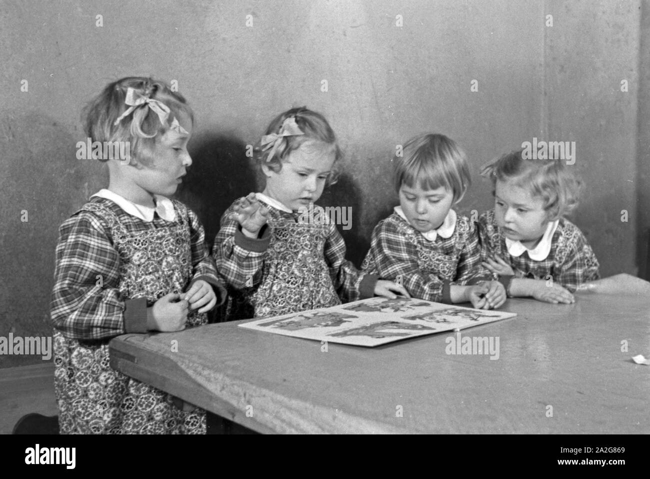 Die Vierlinge Knipser betrachten ein Bilderbuch, Deutschland 1930er Jahre. Il Knipser's quadrupletto ragazze con un storybook, Germania 1930s. Foto Stock