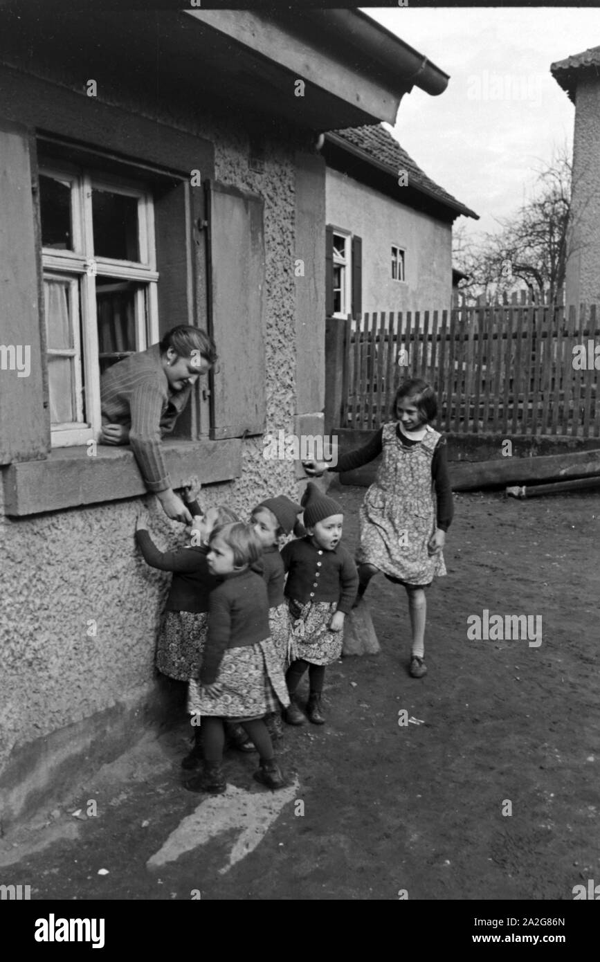 Die Vierlinge Knipser bekommen ein Butterbrot aus dem Fenster heraus, Deutschland 1930er Jahre. La Knipser quadrupletto ragazze ottenendo un sandwich frm fuori della finestra, Germania 1930s. Foto Stock