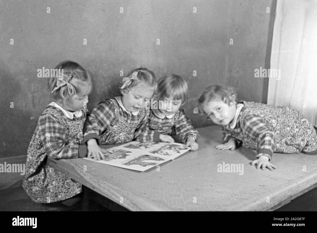 Die Vierlinge Knipser betrachten ein Bilderbuch, Deutschland 1930er Jahre. Il Knipser's quadrupletto ragazze con un storybook, Germania 1930s. Foto Stock