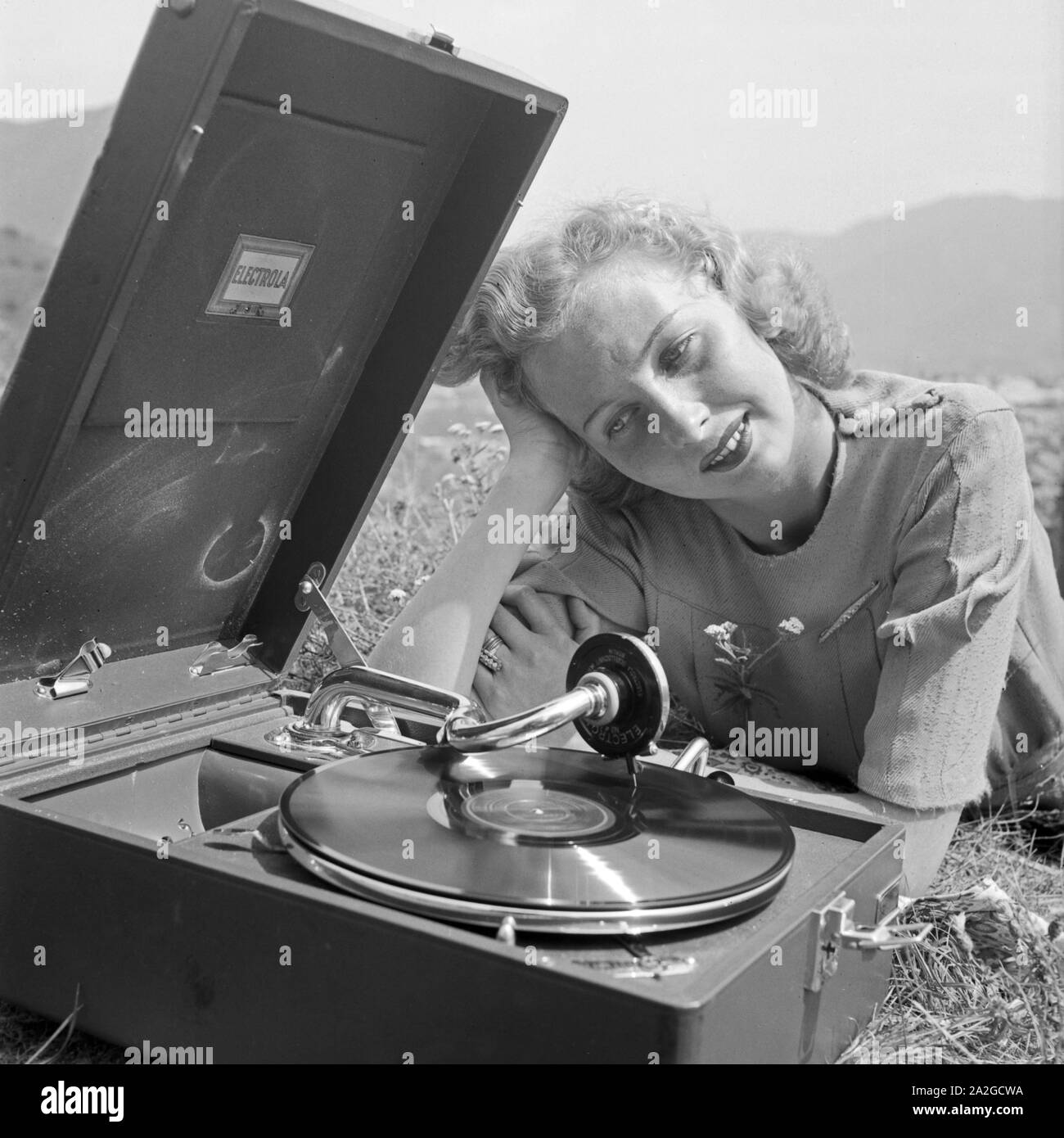 Eine junge Frau mit dem Electrola Koffer Grammofon und hört das Stück 'Frühlingstag' von Barnaba von Geczy, Österreich 1930er Jahre. Una giovane donna con un grammofono Electrola e un Electrola shellac record, Austria 1930s. Foto Stock