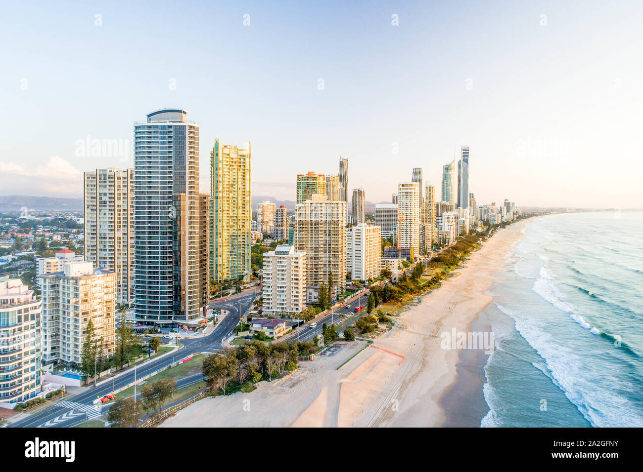 Antenna di sunrise skyline proprio sulla spiaggia. Bella la luce del mattino sulla Gold Coast holiday hotel destinazione dall'oceano. Foto Stock