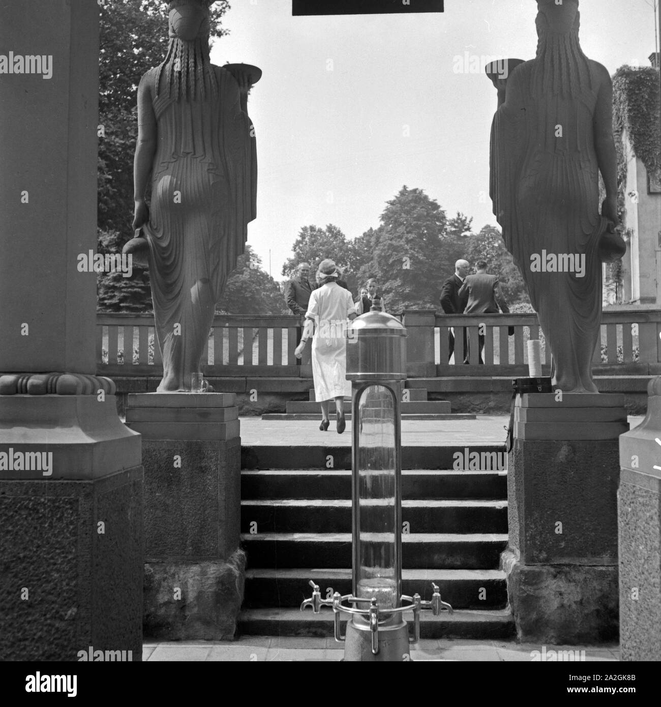 Eine Krankenschwester holt Kurgästen in Bad Homburg Wasser aus der Heilquelle, Deutschland 1930er Jahre. Un infermiere portando acqua da una molla di medicinali per ospiti termali di Bad Homburg, Germania 1930s. Foto Stock