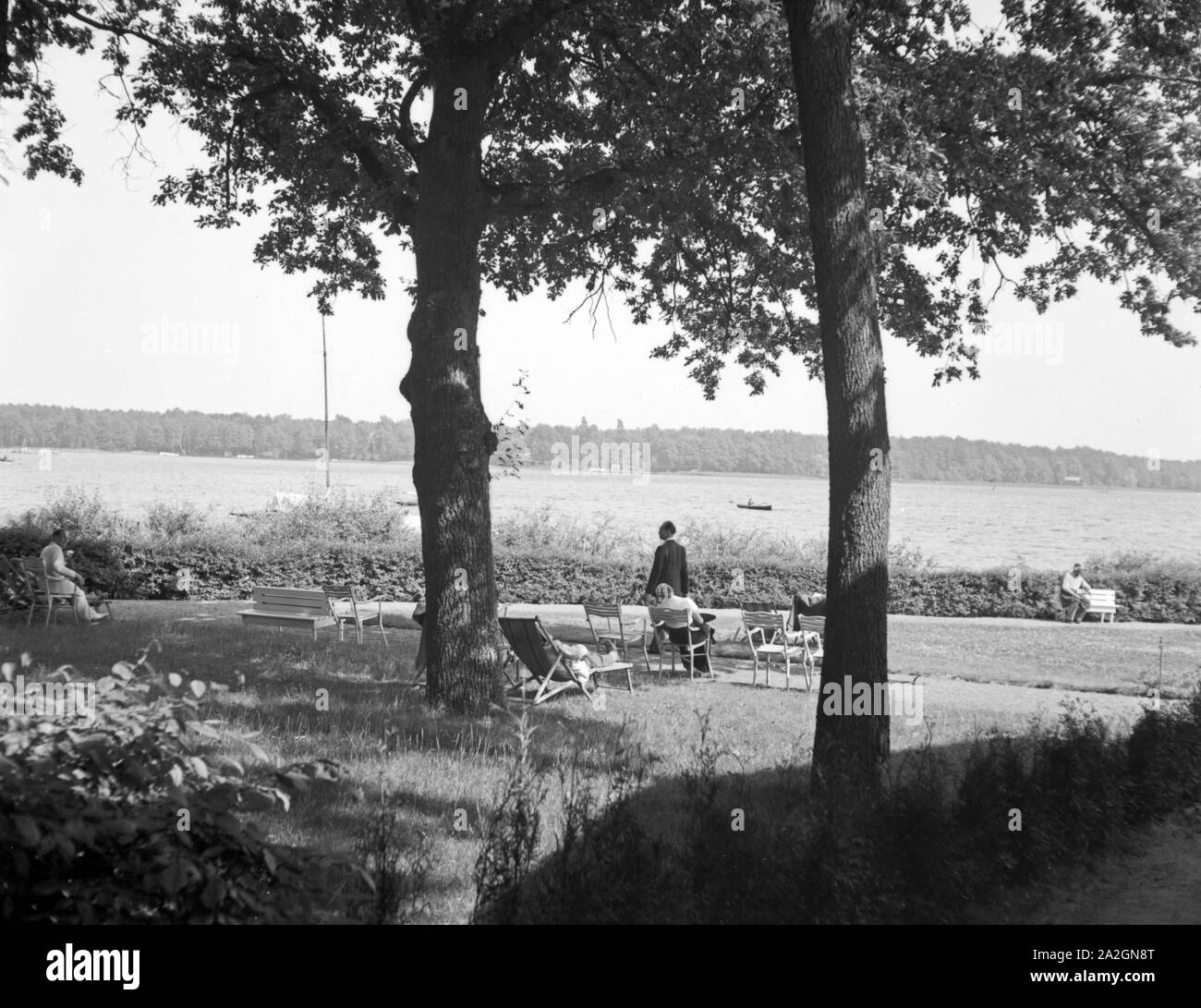 Menschen erholen sich an der Uferpromenade eines vede, Deutschland 1930er Jahre. Persone rilassarsi all'ombra a un lago, Germania 1930s. Foto Stock