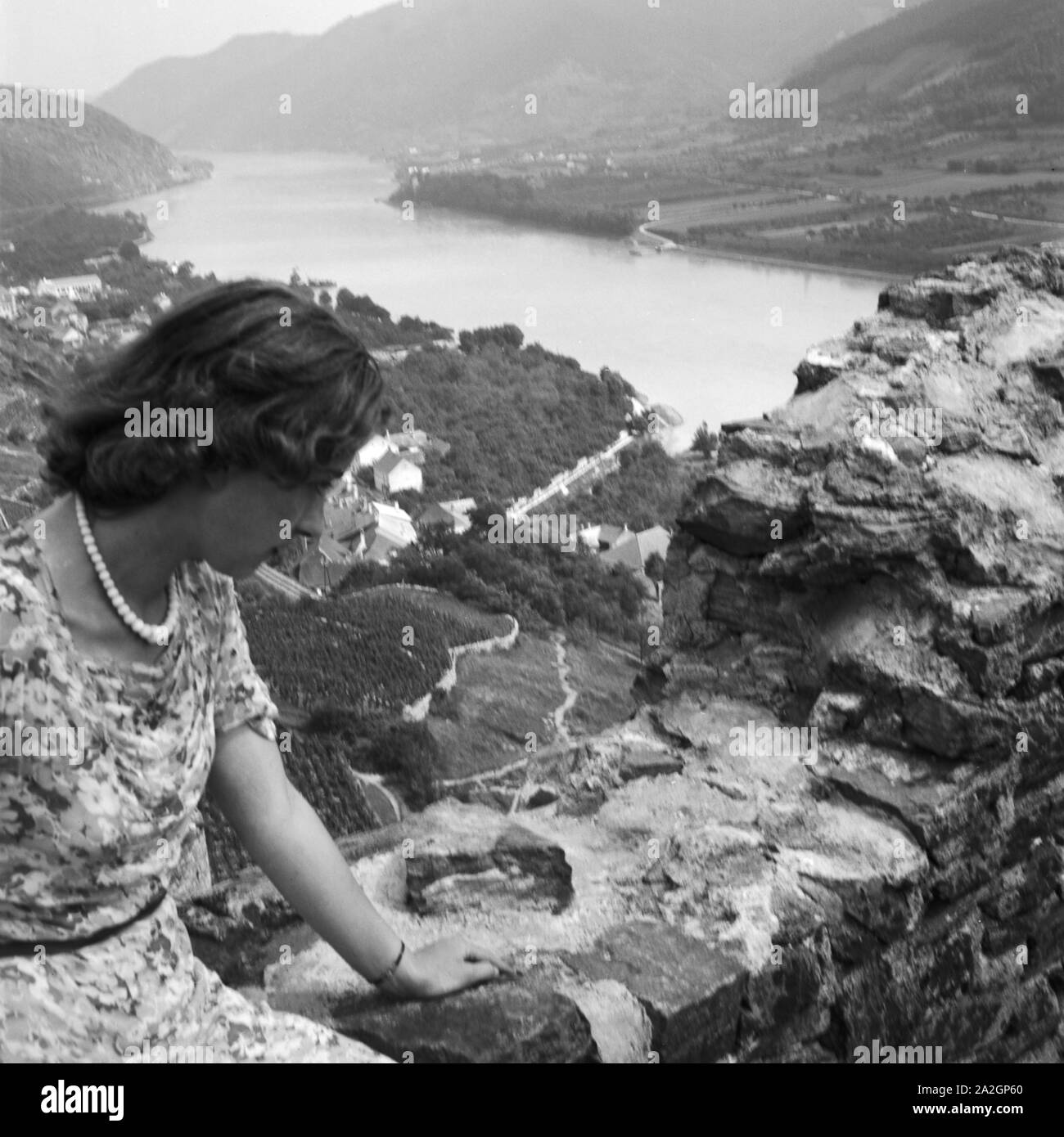 Eine junge Frau sitzt auf einer Mauer einer Burgruine in der Wachau in Österreich, Deutschland 1930er Jahre. Una giovane donna seduta nei resti di un antico castello nell'area di Wachau in Austria, Germania 1930s. Foto Stock