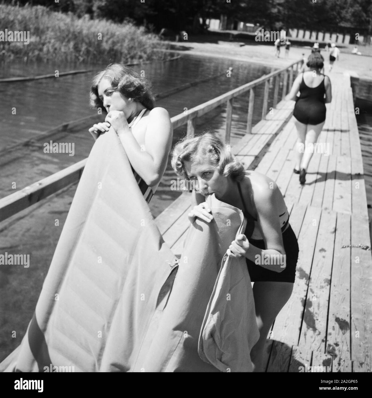 Zwei junge Frauen blasen ihre Luftmatratze un einem vedere in der Wachau in Österreich auf, Deutschland 1930er Jahre. Due giovani donne che soffia su loro materassi di aria su un lago in area di Wachau in Austria, Germania 1930s. Foto Stock