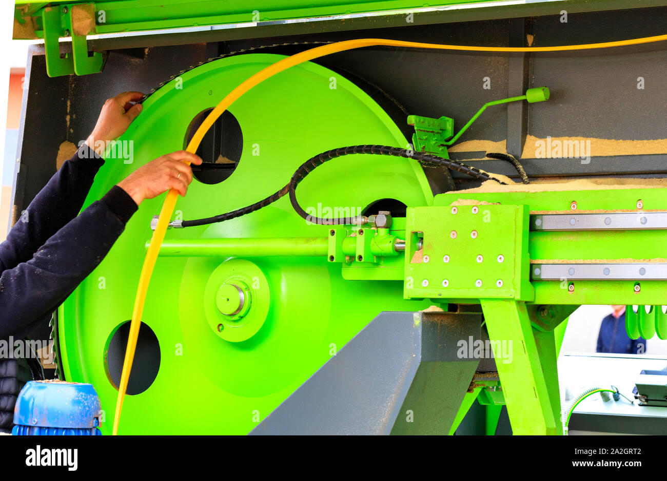 Macchine per la lavorazione del legno, lavoratore sostituisce una sega a nastro ad una moderna segheria automatica. Foto Stock