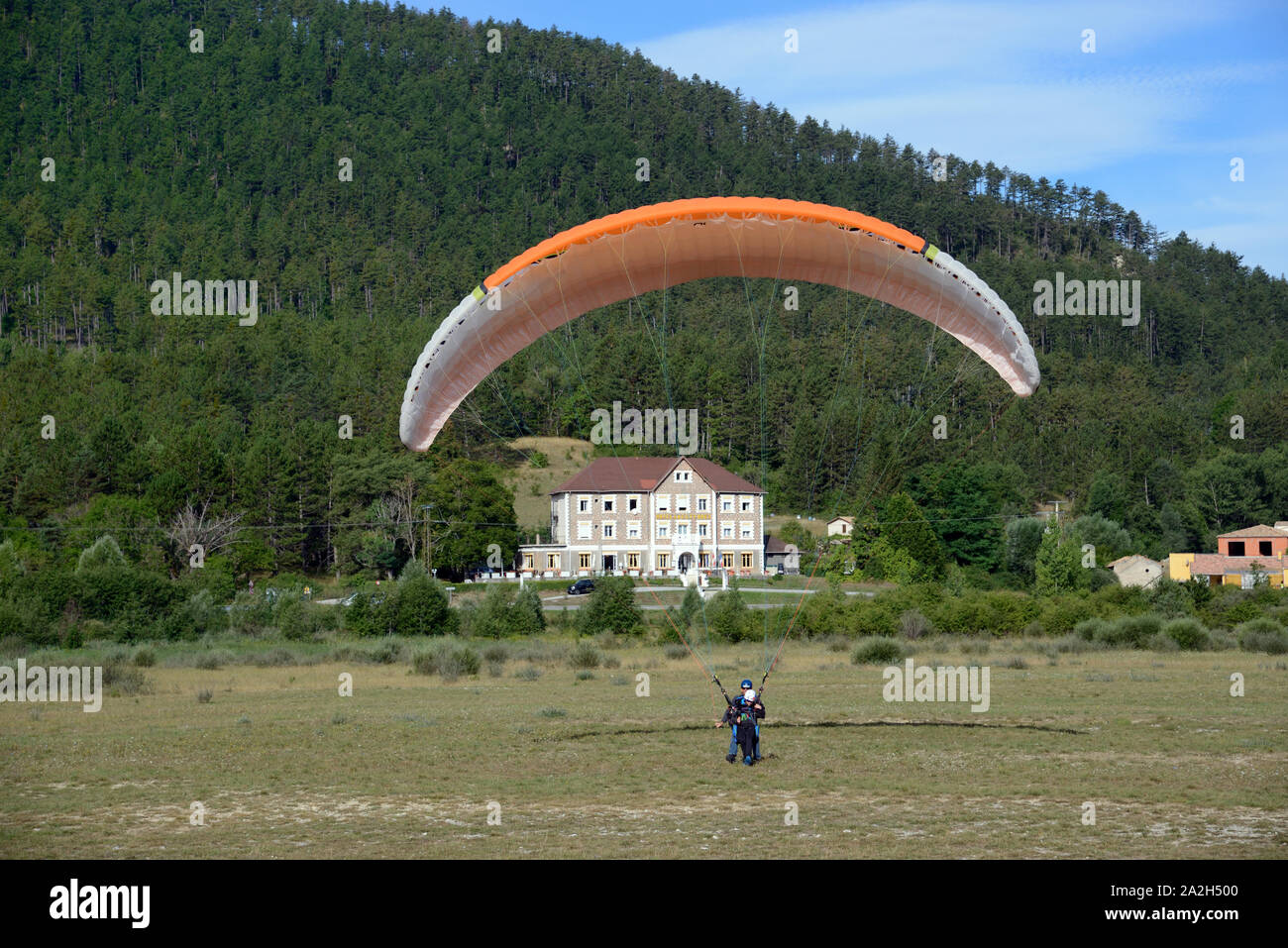 Deltaplano in atterraggio a Saint-André-les-Alpes, con Hotel storico in background, il Verdon Parco Regionale Alpes-de-Haute-Provence Provence Francia Foto Stock