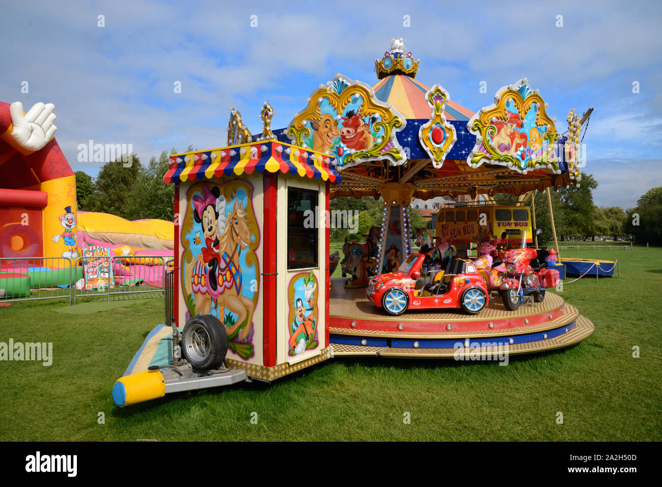 Il kitsch o giostra decorativo, rotatoria, Merry-Go-rotonda o fiera del divertimento con automobili giocattolo sul terreno di ricreazione o parco giochi Stratford-upon-Avon Inghilterra Foto Stock