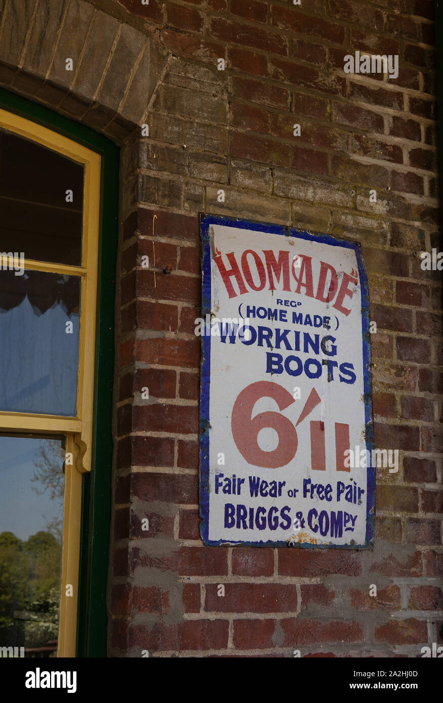 Vecchio annuncio sulla stazione ferroviaria parete per stivali da lavoro Foto Stock