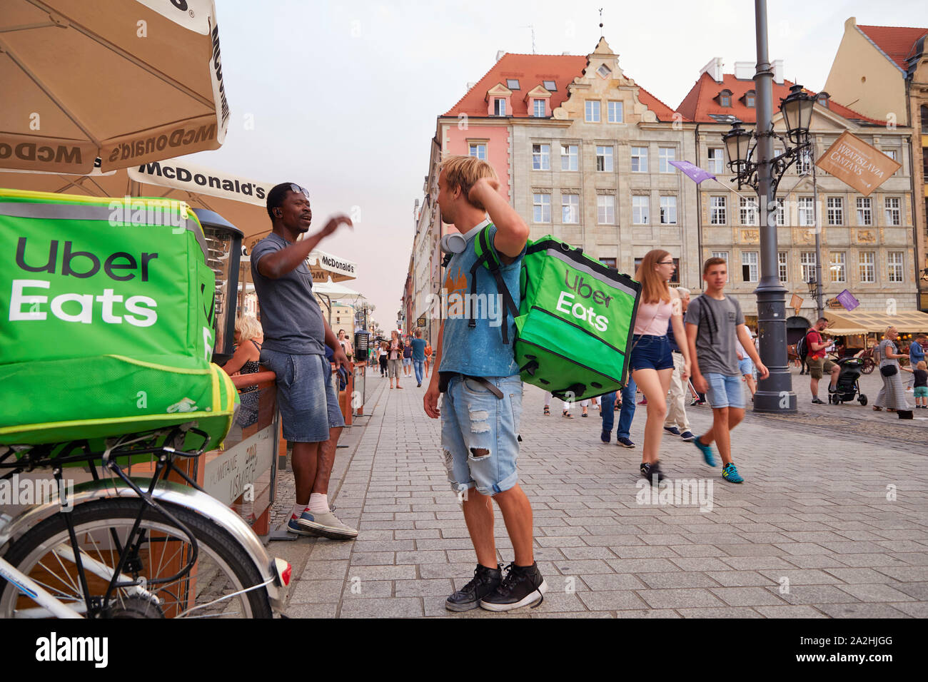 Polen Wroclaw Uber mangia il driver su una bici in attesa per il cibo nel corso di una conversazione con un collega, un compagno di lavoro 8-8-2019 foto Jaco Klamer Foto Stock