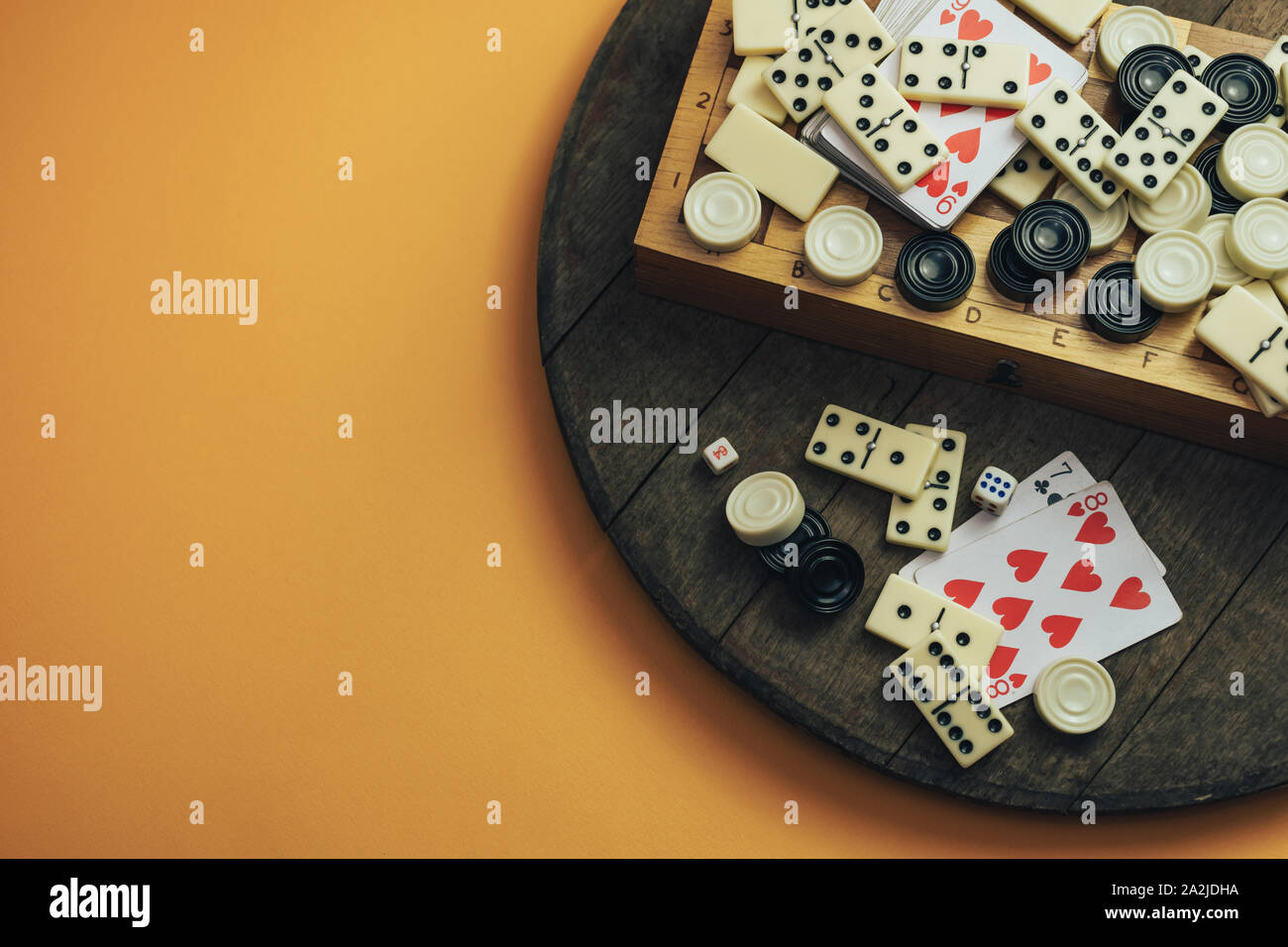 Vari giochi da tavolo scacchiera, giocando a carte, domino su un vecchio  tavolo di legno sfondo arancione Foto stock - Alamy