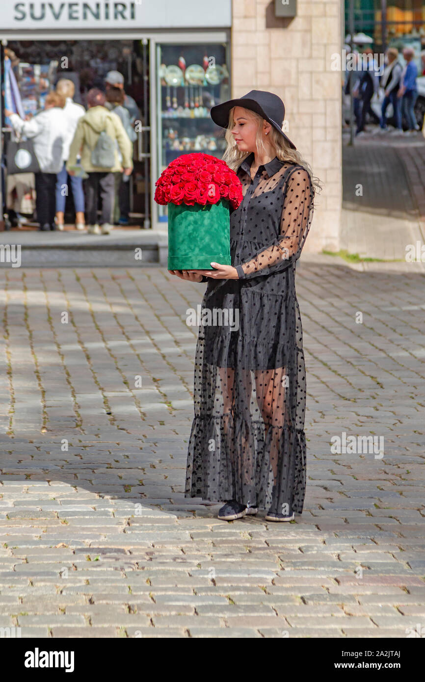 Giovani donne vestite di nero che tiene a fiori di colore rosso in piazza del Municipio, Riga, Lettonia, Foto Stock