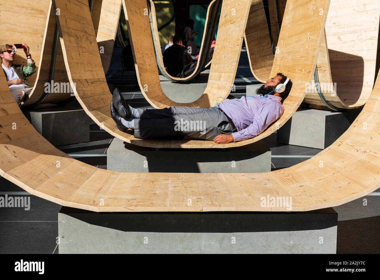 Un visitatore si rilassa sul si prega di essere insediato l'installazione da Paul Cocksedge presso il London Design Festival 2019, Finsbury Avenue Square, Broadgate, Londra Foto Stock