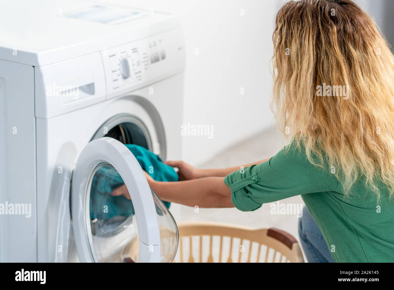 Giovane donna, il carico della macchina di lavaggio per la pulizia laundrys . Foto Stock