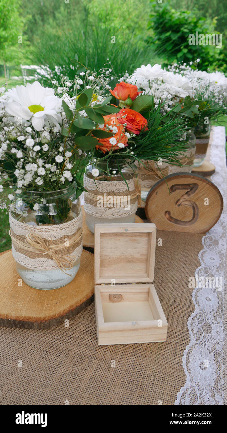 Tabella numero tre con legno arredamento retrò - Daisy bianca e arancione rose in vasi Foto Stock