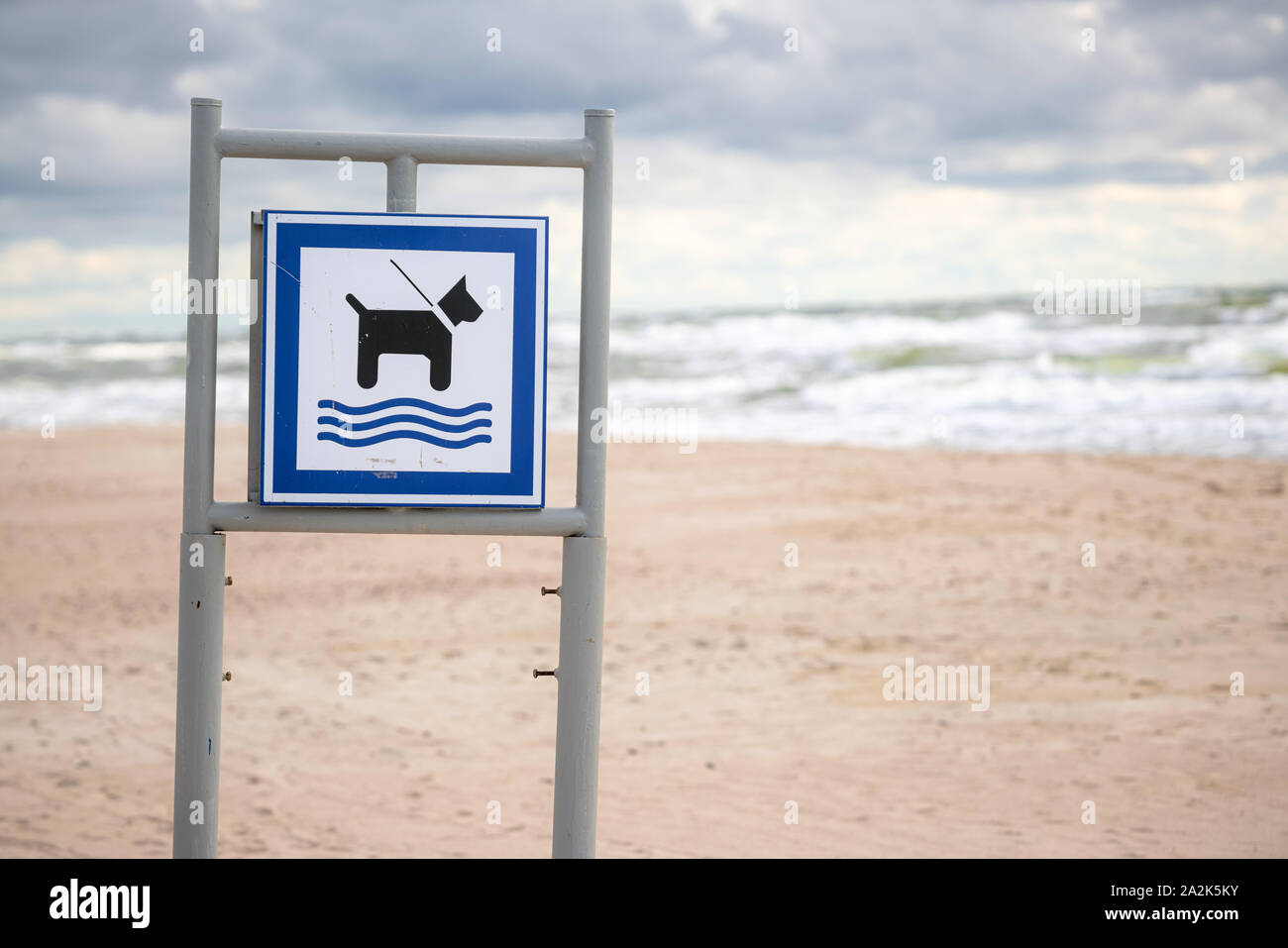 Dog Beach segno con la sabbia e le onde che si infrangono in background. Messaggio post, affissioni con segno permettendo i cani in spiaggia Foto Stock