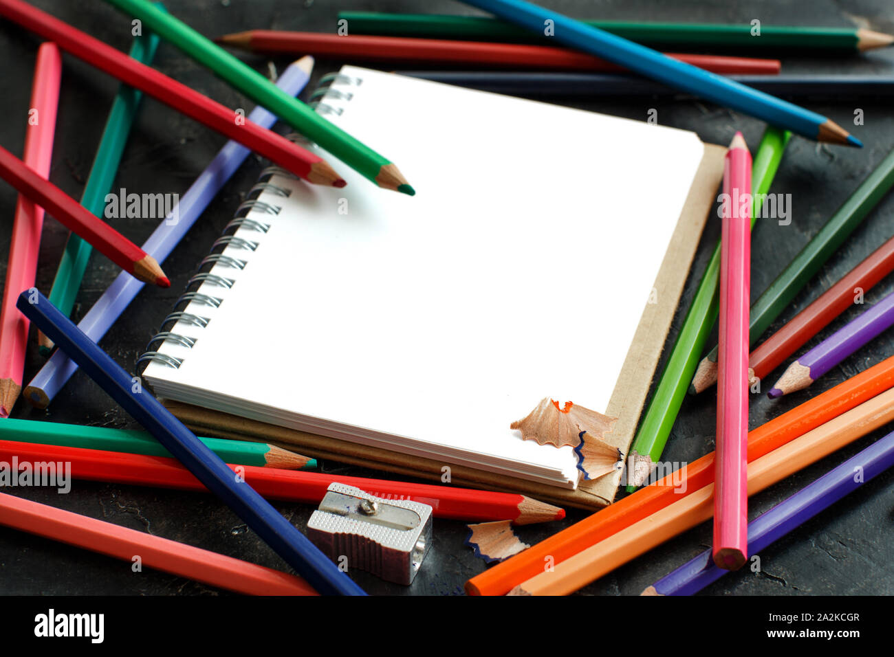 Disegno-pad e matite a colori su sfondo scuro Foto Stock