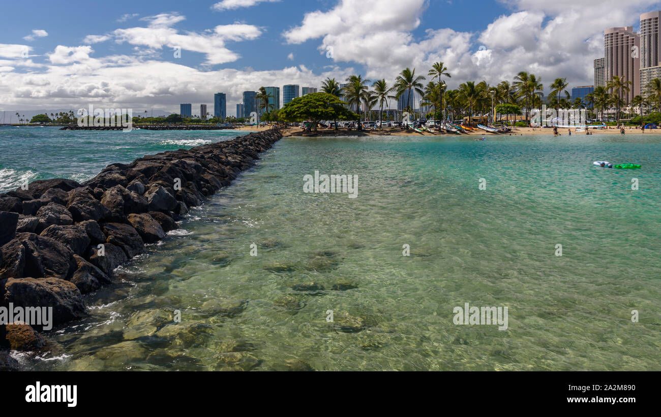 Vista verso una spiaggia tropicale, lungo un frangiflutti. La spiaggia è la spiaggia di Waikiki, Honolulu, Hawaii Foto Stock