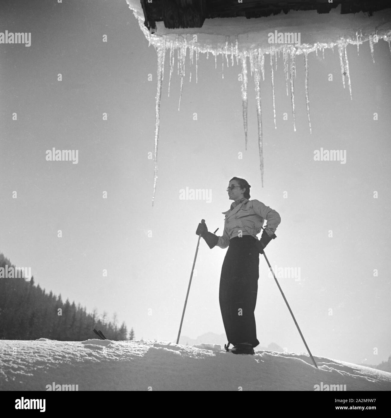 Ein junge Frau auf Skiern in einer Winterlandschaft, Deutschland 1930er Jahre. Una giovane donna con gli sci in un paese delle meraviglie invernali, Germania 1930s. Foto Stock