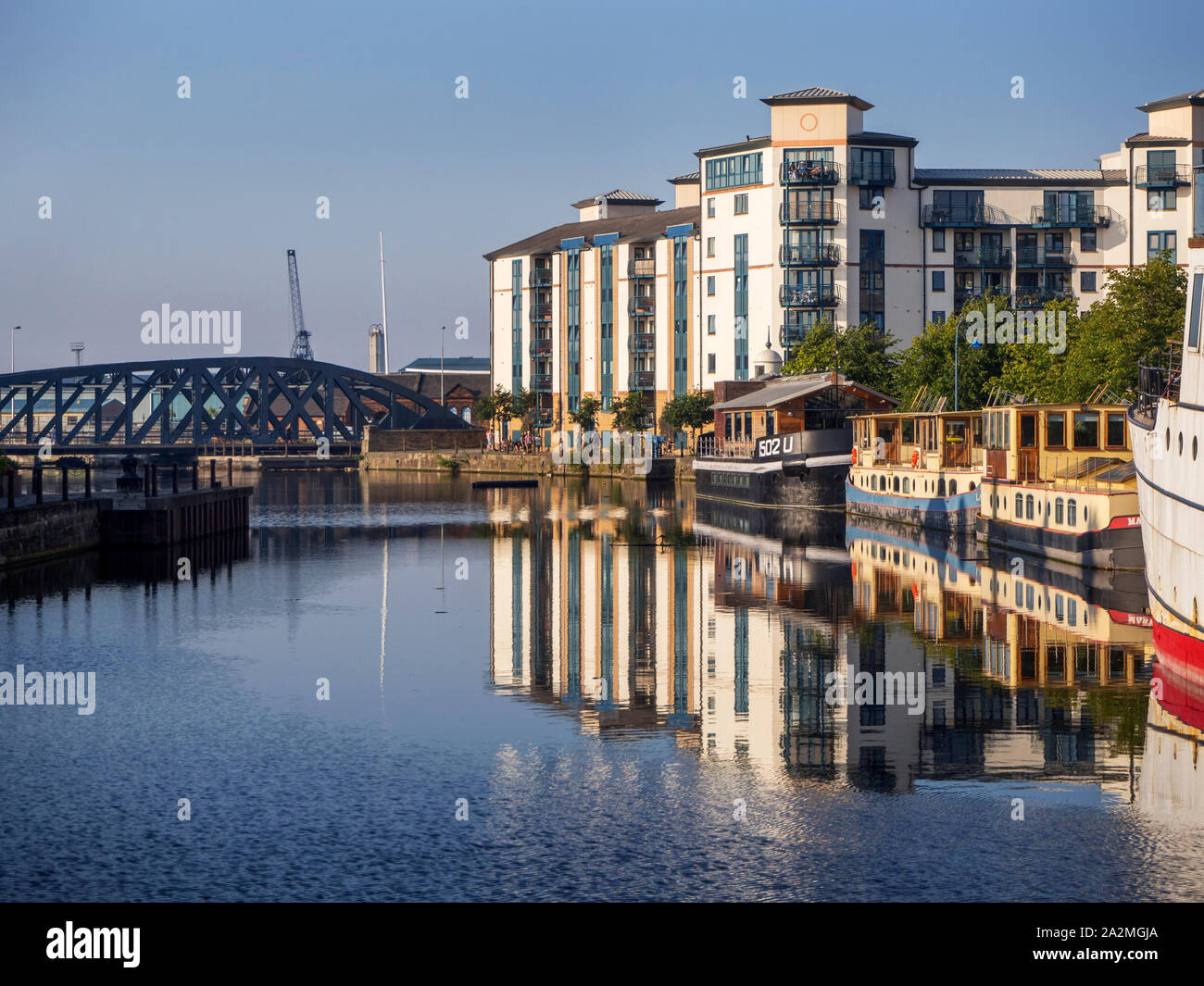 Barche ormeggiate e moderni appartamenti riflessa nell'acqua di Leith su una soleggiata sera Leith città di Edimburgo in Scozia Foto Stock