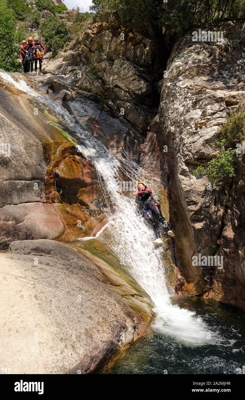 I turisti in una naturale scorrere acqua canyoning la Cascades de Purcaraccia, Quenza nelle montagne di Bavella Corsica Francia - Corsica attività di avventura Foto Stock
