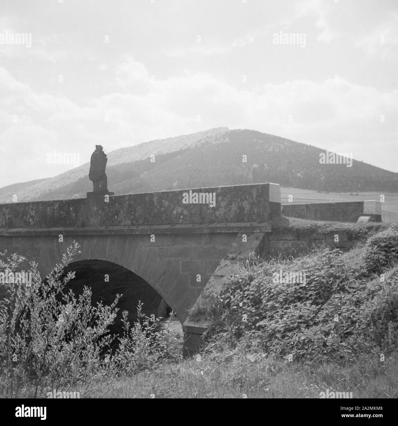 Kleine Brücke mit Heiligenfigur im Odenwald, Deutschland 1930er Jahre. Piccolo ponte con la scultura di un santo nella regione di Odenwald, Germania 1930s. Foto Stock