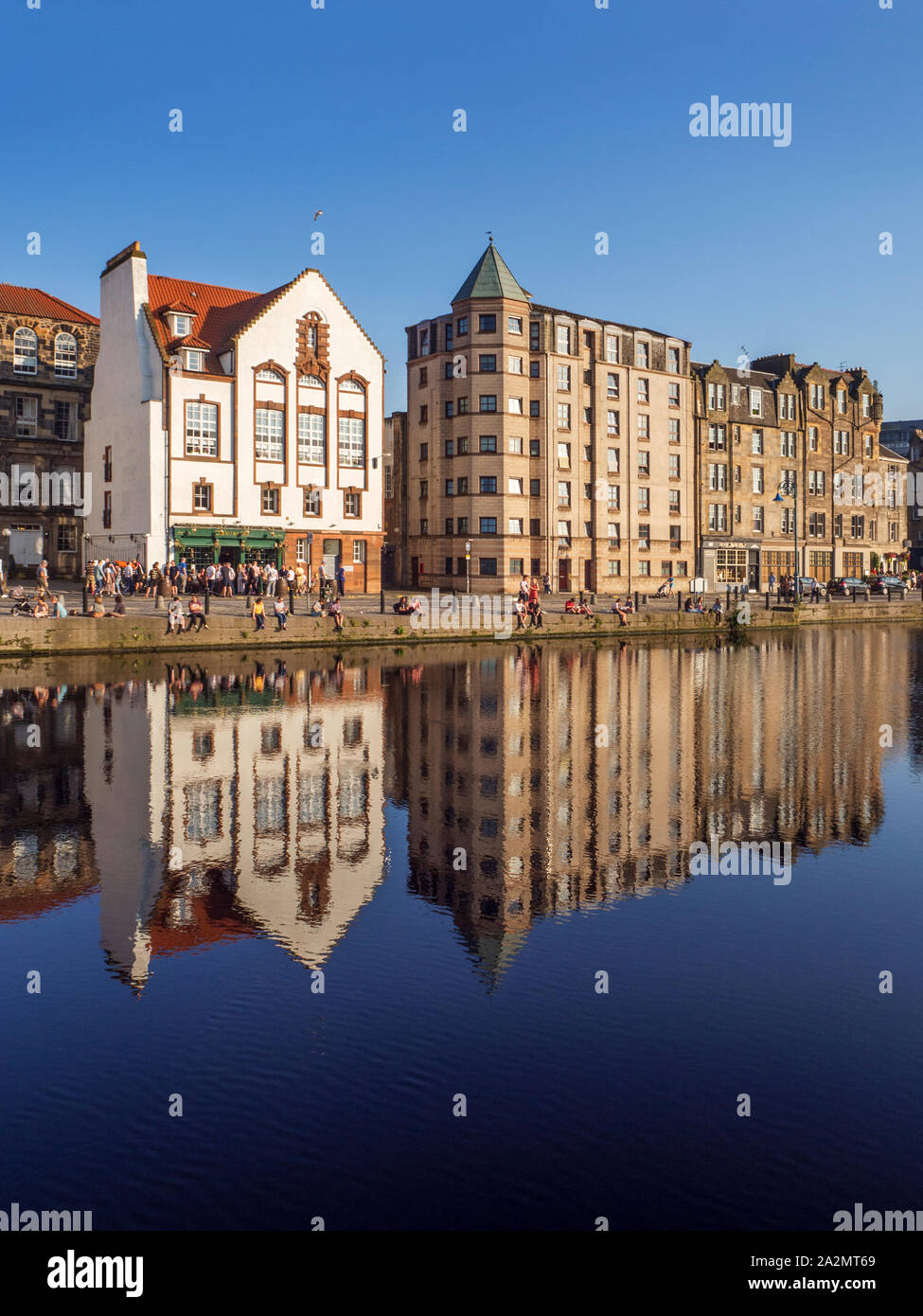 Edifici antichi lungo la riva riflessa nell'acqua di Leith in una serata estiva Leith città di Edimburgo in Scozia Foto Stock