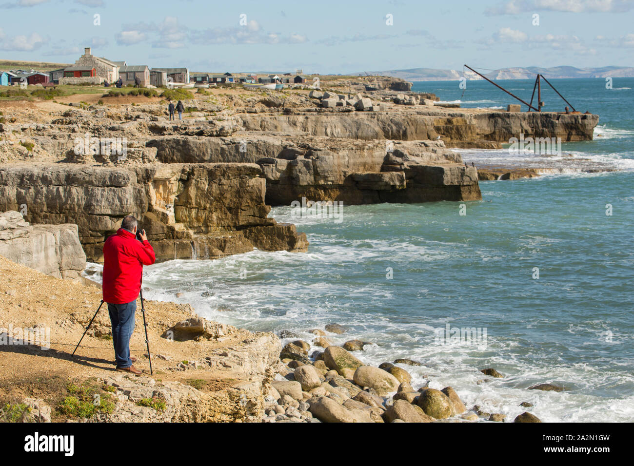 Un fotografo in una giornata ventosa di scattare le foto utilizzando un treppiede sulle scogliere di Portland Bill, isola di Portland in Inghilterra UK GB Foto Stock