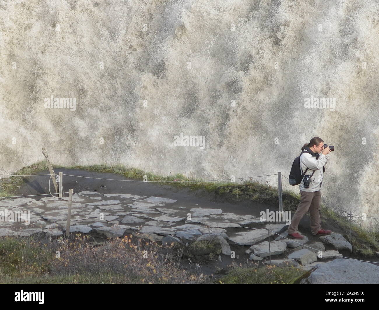 Un fotografo si concentra sul volume di acqua a cascata su un 44m di caduta a Dettifoss, la cascata più grande in Islanda Foto Stock