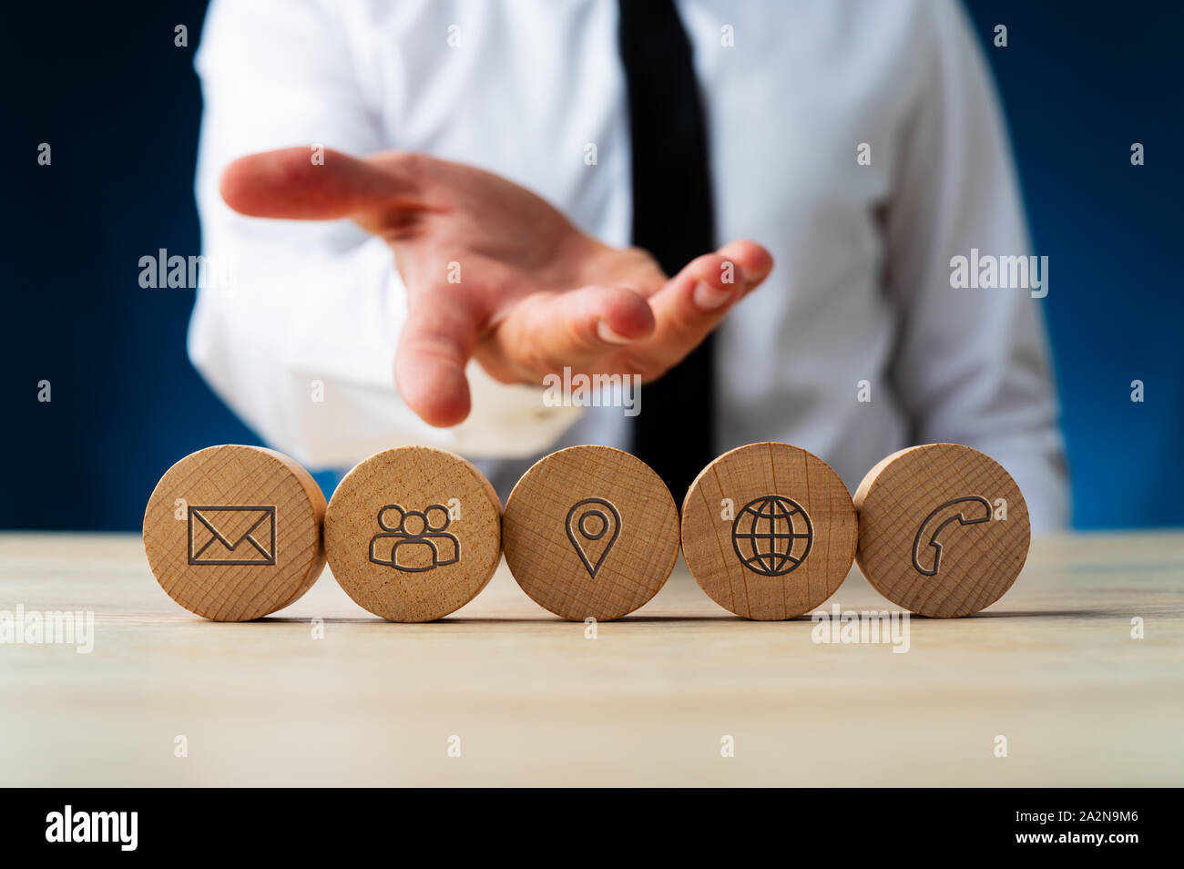 La mano di un uomo di affari nel presentare il gesto che mostra cinque cerchi di legno con contatto e icone di informazioni su di essi. Foto Stock