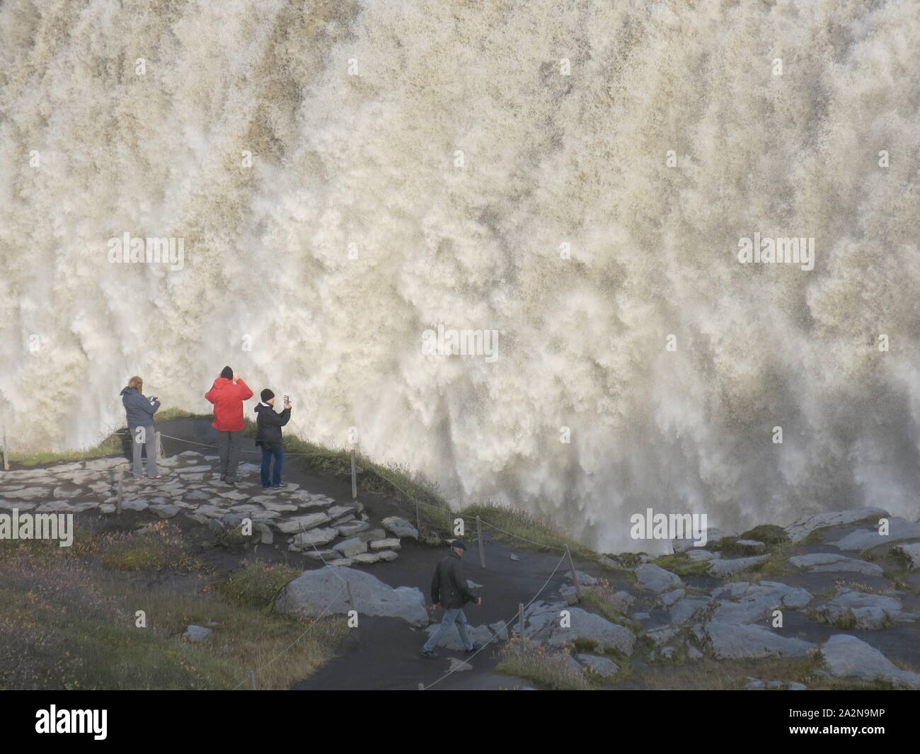 I turisti fotografare Dettifoss, la cascata più grande in Islanda lo scarico di una potente torrente di acqua nel canyon sottostante. Foto Stock