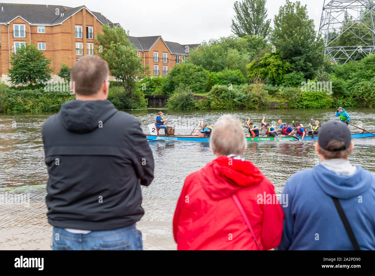 Persone in piedi sulla riva del fiume a guardare la gara di dragon boat 2019 in aiuto di San Rocco's ospizio, tenutasi a Warrington Rowing Club, Cheshire, en Foto Stock