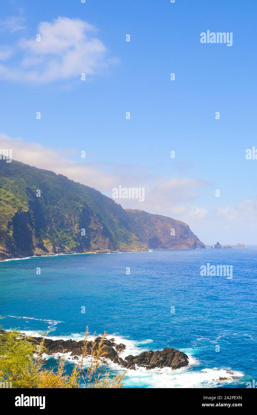 Incredibile costa settentrionale dell'isola di Madeira, Portogallo fotografata da villaggio Seixal. Belle scogliere ripide coperte da foresta verde. Isola portoghese nell'Oceano Atlantico. Le destinazioni turistiche. Foto Stock