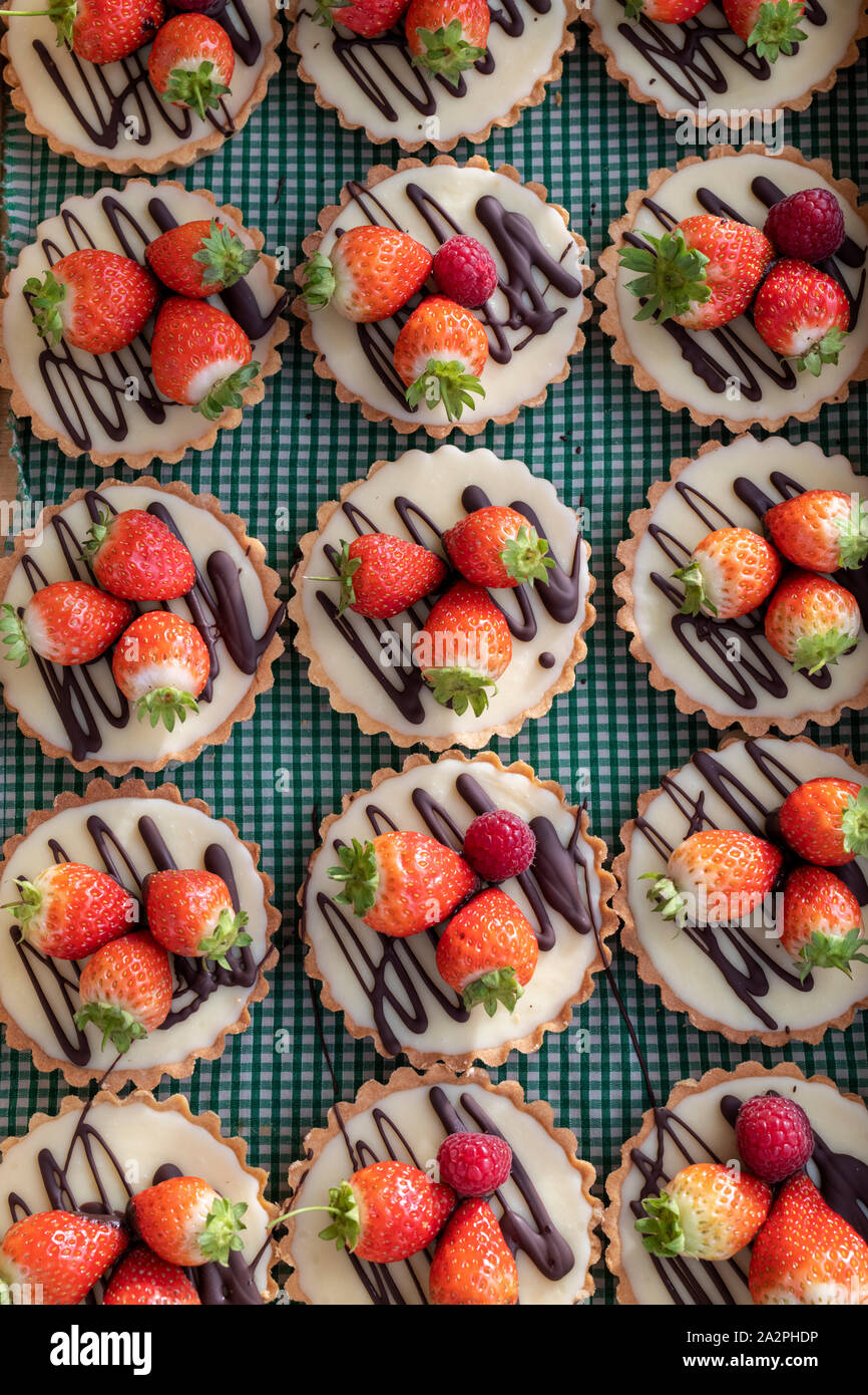 Il cioccolato bianco e le crostate di fragole su un sfondo gingham Foto Stock