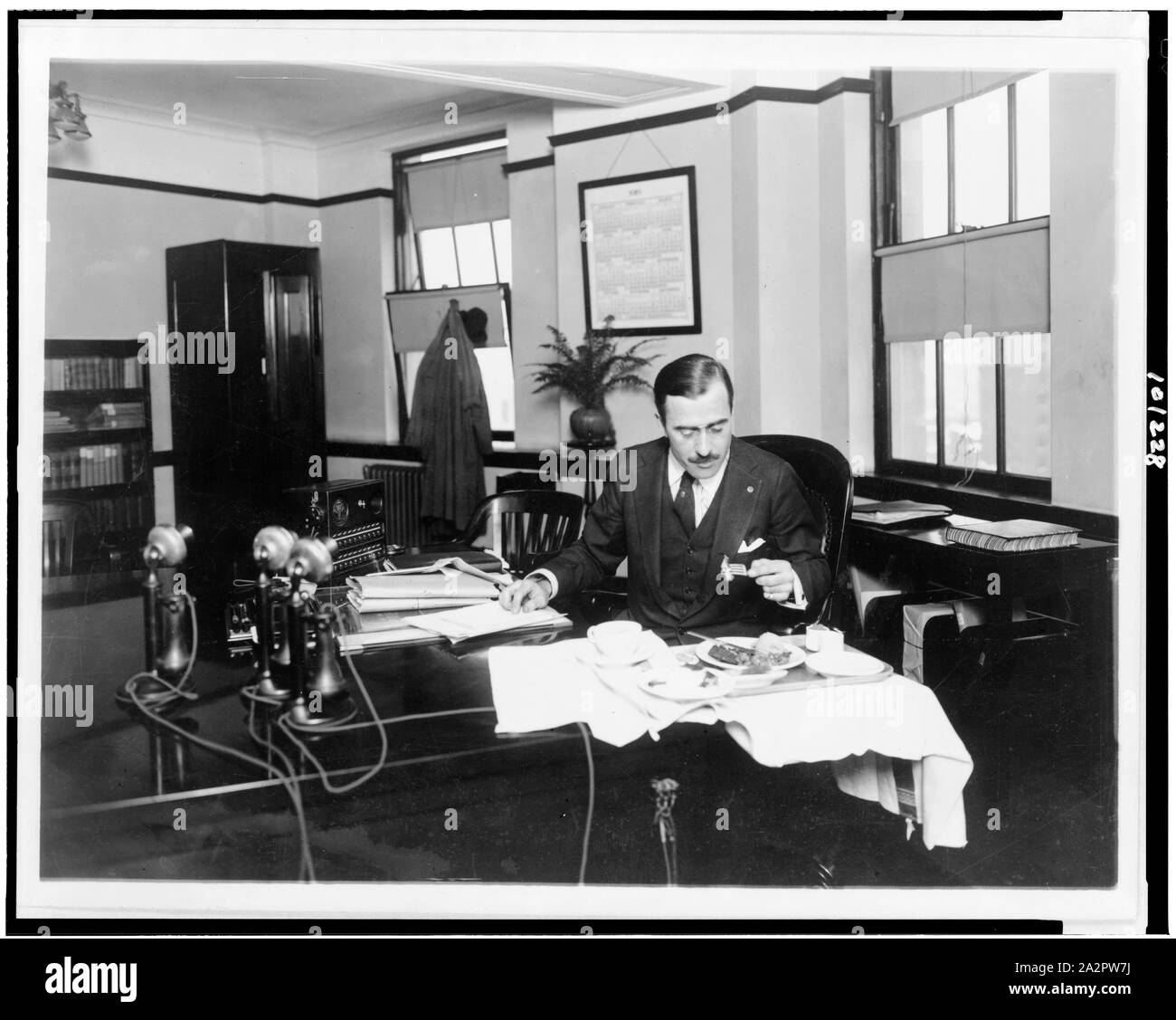 R.G. Cholmeley-Jones, Direttore della guerra rischio Bureau, mangiare il pranzo alla sua scrivania Foto Stock