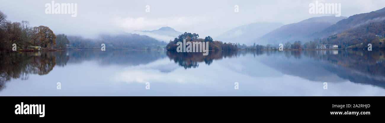 Una vista panoramica di Grasmere su una tranquilla mattina autunnale con specchio calma riflessioni del Daffodil Hotel, Isola, boathouse e fells. Foto Stock