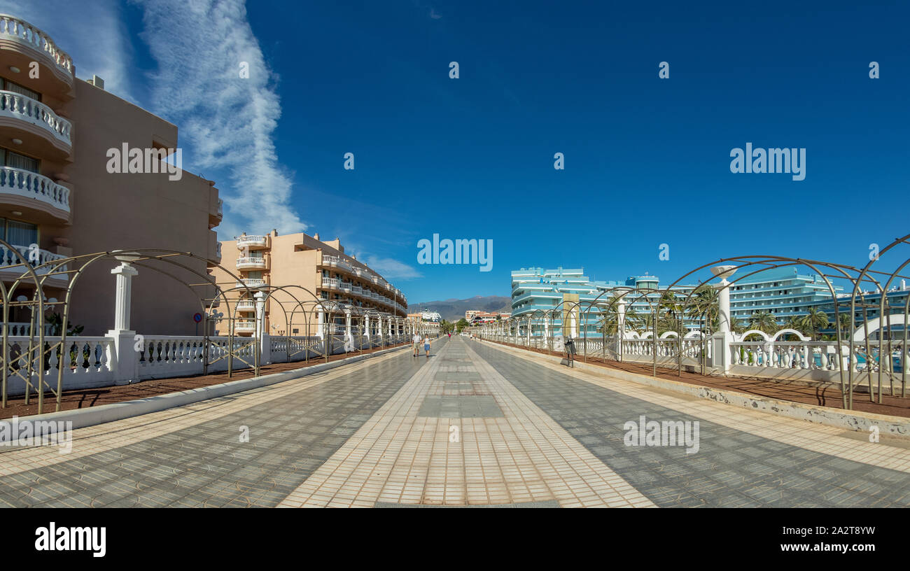 Ampia strada pedonale nel centro turistico di Playa de las Americas. Super grandangolo vista panoramica. Chiara giornata soleggiata con molto poche splendide nuvole bianche Foto Stock