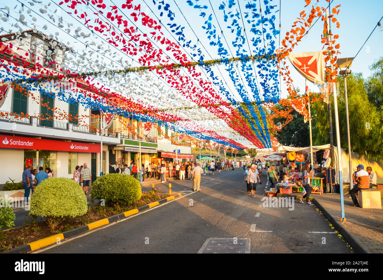 Loreto, Madeira, Portogallo - 7 SET 2019: Bella colorata decorazione di strada durante la celebrazione della festa religiosa. Fiori di carta appeso in aria. La gente celebra, bancarelle con prodotti alimentari. Foto Stock