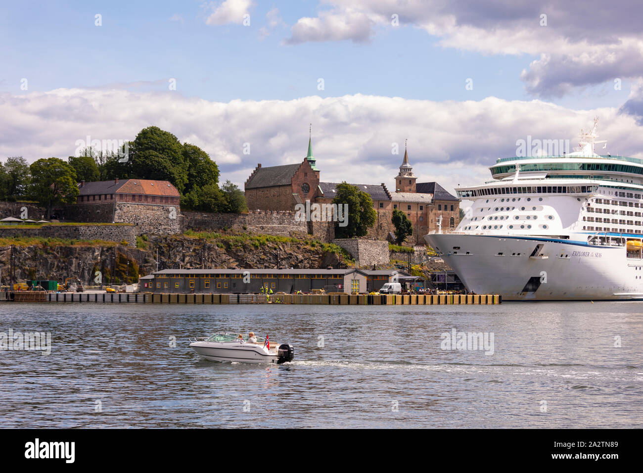 OSLO, Norvegia - Piccola imbarcazione passa il Explorer dei mari a Royal Caribbean Cruise nave ormeggiata presso la Fortezza di Akershus Oslo waterfront. Foto Stock